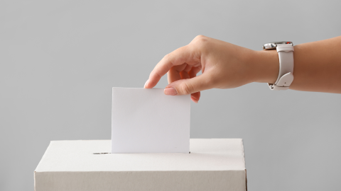 Imagen de una persona introduciendo un voto en una urna. 